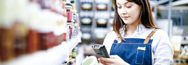 Mujer verifica el valor nutricional de un alimento con un celular en el supermercado