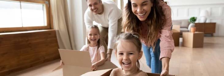 Padres juegan con sus hijas a las carreras de cajas para divertirse y compartir tiempo en casa