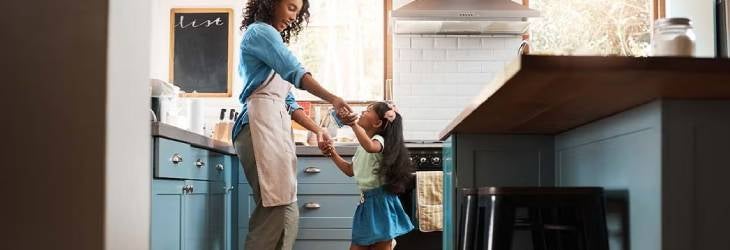 Una mamá y su hija haciendo juegos lúdicos en la cocina