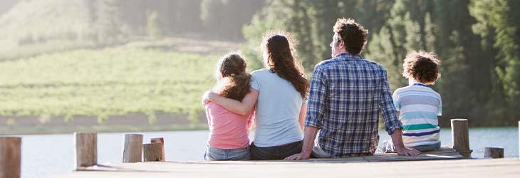 Familia en el muelle junto al lago toma el sol para tener niveles adecuados de vitamina D