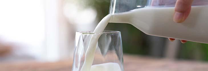 Un alimento rico en vitamina D como la leche de una botella que se vierte en un vaso de vidrio