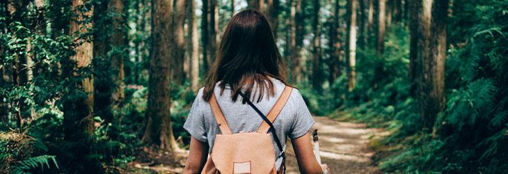 Mujer camina por el bosque para beneficiar su nivel cardiorrespiratorio