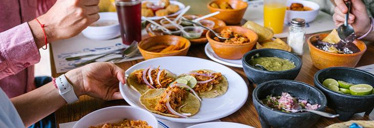 Personas alrededor de una mesa comparten comida balanceada y trabajan sus relaciones sociales