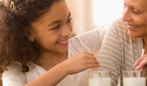 Nieta y abuela bebiendo dos vasos de leche, un alimento con calcio