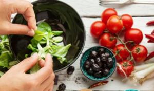 Preparación de ensalada con tomate, pimentón y espinacas, que son alimentos con vitamina A