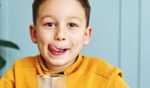 Niño tomando un vaso de leche, alimento que contiene calcio